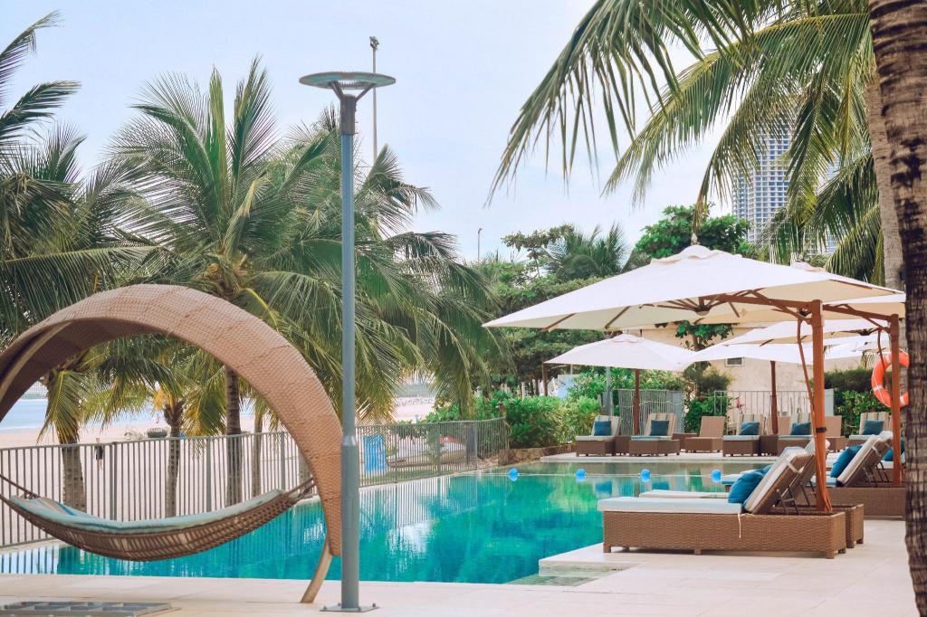 Outdoor pool at Fusion Suites Da Nang, with loungers and the hotel behind the deck