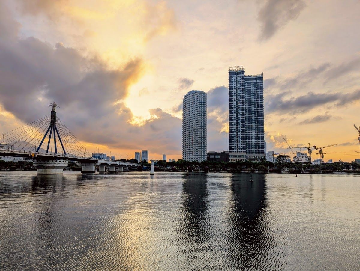 Da Nang city from the Han River at sunset, showing the Nguyen Van Troi Bridge and high-rise hotels reflected in the water