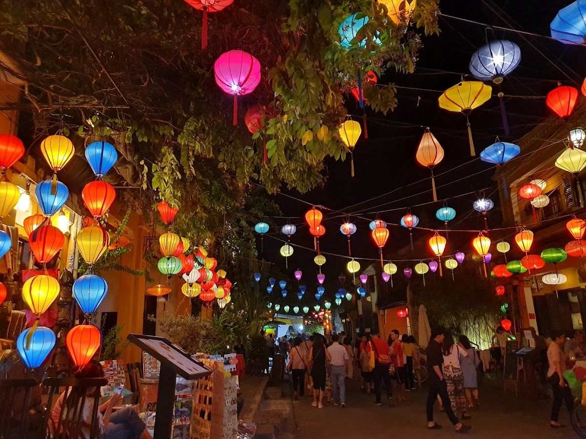 Colourful silk lanterns strung between trees over a pedestrian street in Hoi An Ancient Town at night