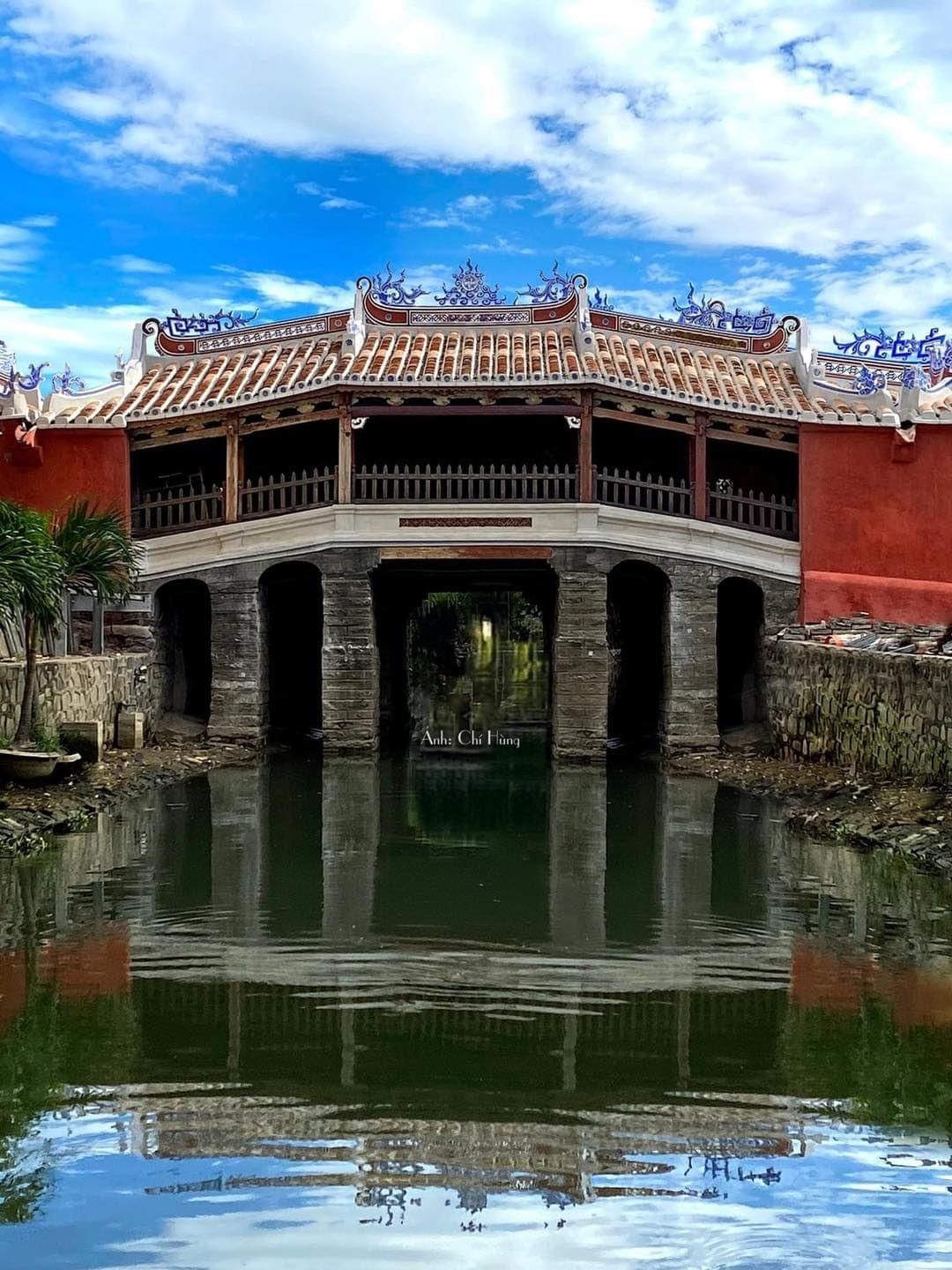 The Japanese Covered Bridge (Lai Vien Kieu) in Hoi An Ancient Town, a 400-year-old wooden structure spanning a small canal surrounded by lanterns and timber shophouses
